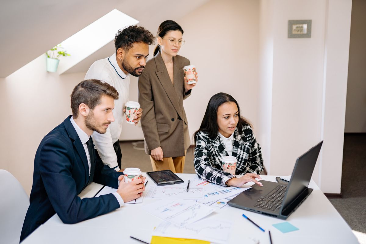 A multicultural technology team working together around a laptop